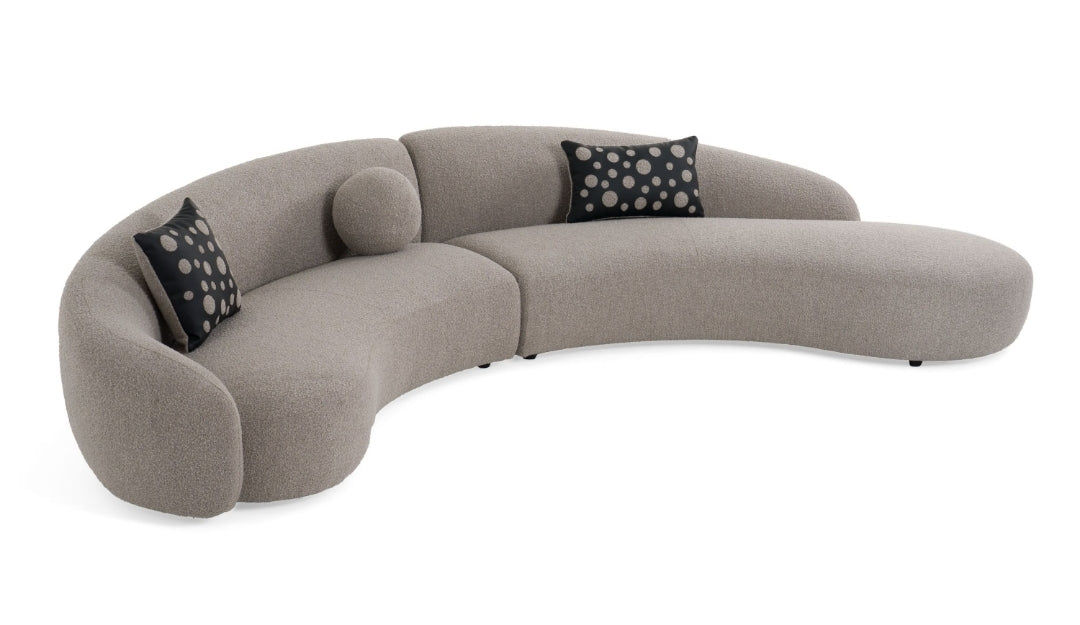 Glam Curved Sectional Sofa upholstered in taupe fabric with black and taupe accent pillows
